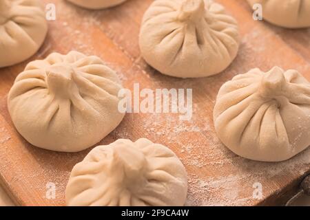 Homemade raw khinkali dumplings on wooden board Stock Photo