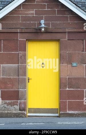 yellow front door on red sandstone cottage house - Scotland, UK Stock Photo