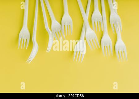 Plastic tableware on a yellow background with free space. Disposable tableware Stock Photo