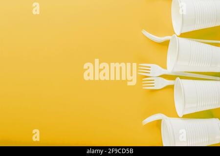 Plastic tableware on a yellow background with free space. Disposable tableware Stock Photo