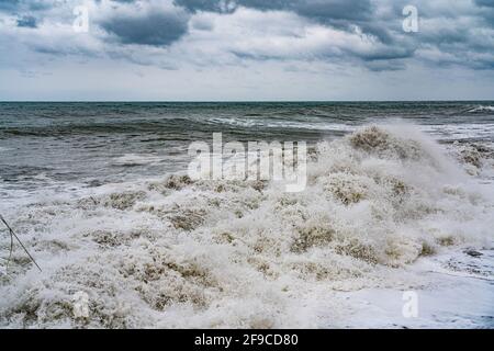 crashing wave on a stormy sea against a cloudy sky background Stock Photo