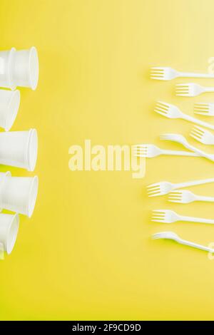 Plastic tableware on a yellow background with free space. Disposable tableware Stock Photo