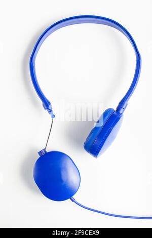 Isolated image of a blue headphone with adjustable head band. One of the ear pieces is broken at the connection side with wires exposed. Concept image Stock Photo