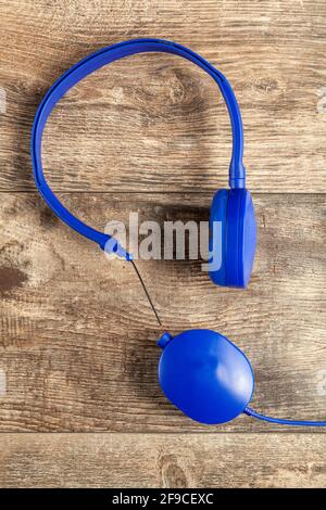 Isolated image of a blue headphone with adjustable head band. One of the ear pieces is broken at the connection side with wires exposed. Concept image Stock Photo