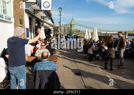 London, UK. 17th Apr, 2021. Londoners Sailing and Drinking at Upper Mall, Hammersmith, overlooking the River Thames. Spring sunshine and a relaxing of COVID-19 lockdown brings sailors to the sailing clubs along the Thames at Hammersmith and drinkers to the many public houses along the Upper Mall. The tide is high and the houseboats resplendent in the afternoon sun. Credit: Peter Hogan/Alamy Live News Stock Photo