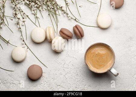Cacao and vanilla macaroons with cup of coffee on a creamy white textured background from above. Macro Stock Photo