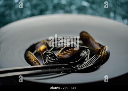 Seafood black spaghetti pasta with clams served on black plate on dark stone Stock Photo