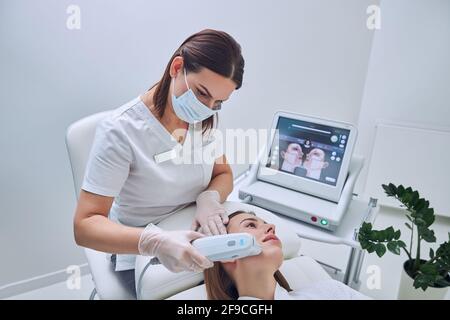 Focused female doctor working with patient in beauty center Stock Photo