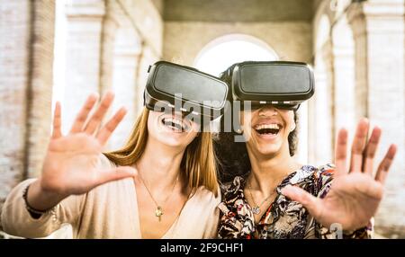 Girlfriends playing on vr glasses outdoors - Virtual reality and wearable tech concept with young people having fun together with headset goggles Stock Photo