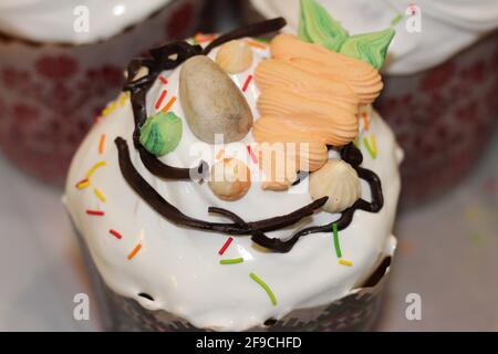 Freshly prepared Easter cakes in paper forms, decorated with fondant, chocolate icing and sugar eggs Stock Photo