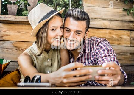Young fashion lover couple at beginning of love story - Handsome man taking selfie with pretty woman at fashion coffee bar - Relationship concept Stock Photo