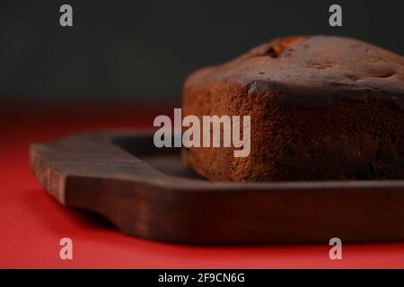 Plum cake, home made delicious christmus cake using raisins ,cashew nuts and dried fruits  which is square in shape placed on wooden base with red col Stock Photo