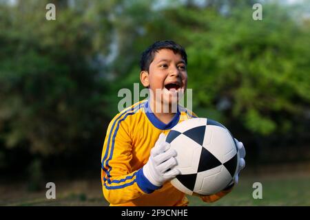 Excited boy football player Holding scored ball Stock Photo
