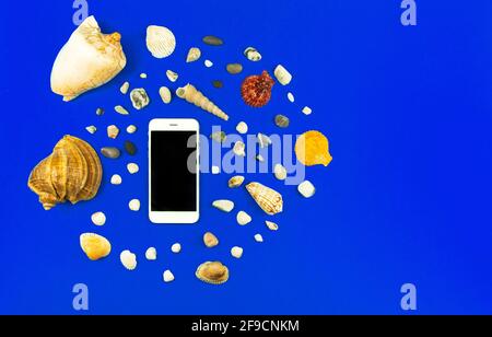 Summer smartphone mockup with seashell and pebbles on a blue background, vacation flat lay composition, top view photo Stock Photo