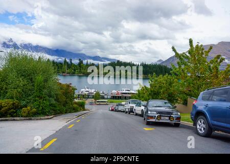 Queenstown New Zealand - February 28 2015; Cars parked along side of road sloping down towards scenic Lake Wakatipu in the tourist town.1 Stock Photo