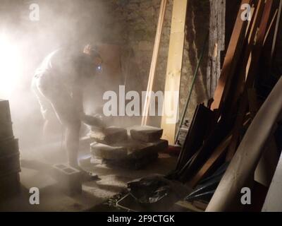 Construction worker cuts cement in a dusty workshop Stock Photo
