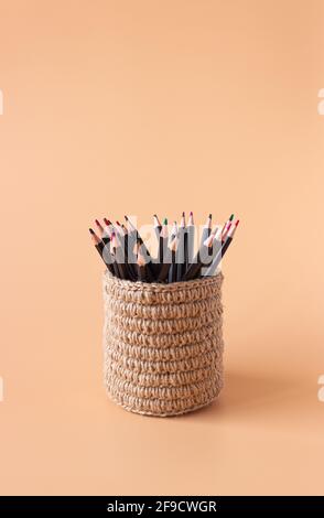 Colored pencils in a wicker basket made of jute on a beige background. Executive Office Stock Photo
