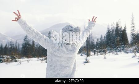 Young woman watching the snowfall and rising her hands on the mountain. High quality photo Stock Photo