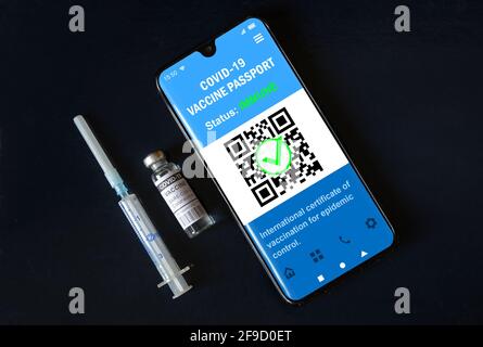 Vaccine vial and health digital passport of COVID-19 vaccination on black background. Coronavirus vaccine certificate app in mobile phone for travel. Stock Photo