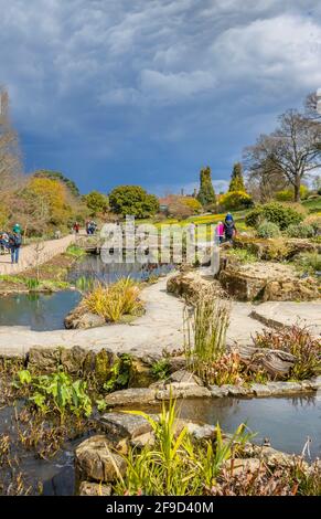 View over the Rock Garden at RHS Garden, Wisley, Surrey, south-east England in spring with gathering grey clouds and impending rain Stock Photo