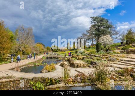 View over the Rock Garden at RHS Garden, Wisley, Surrey, south-east England in spring with gathering grey clouds and impending rain Stock Photo