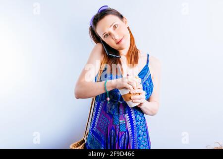beautiful young woman with cup of coffee summer dress and purple glasses talking on the phone on white background Stock Photo