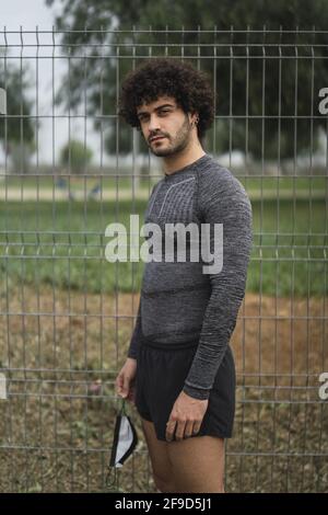 Shallow focus of a young curly-haired man wearing sportswear in a park Stock Photo