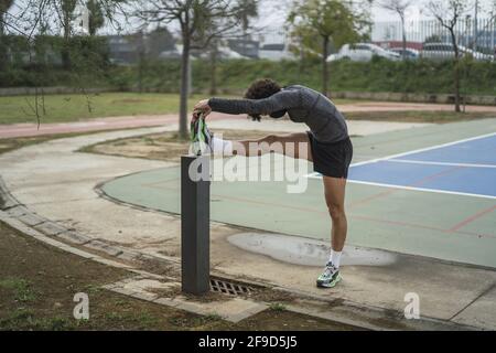 Shallow focus of an adult man in sportswear stretching in a park Stock Photo