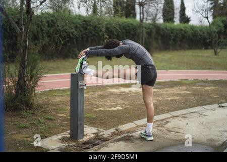 Shallow focus of an adult man in sportswear stretching in a park Stock Photo
