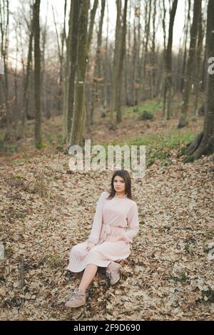 Young dark-haired Caucasian female in an elegant dress posing in the forest Stock Photo