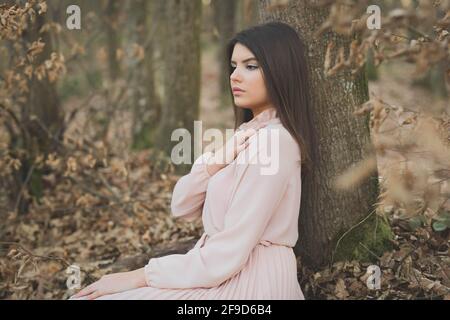 Young dark-haired Caucasian female in an elegant dress posing in the forest Stock Photo