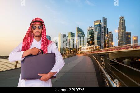 Arab man holding business briefcase in modern city. Concept of overseas international business of Arab businessman. Stock Photo