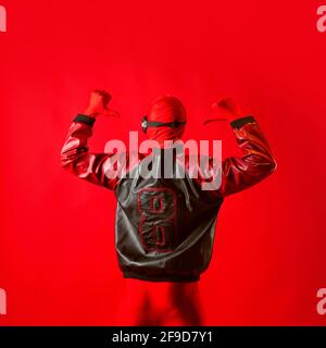 A funny super hero in a red leotard and protective glasses. The man in red on a red background. Stock Photo