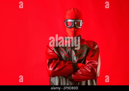 A funny super hero in a red leotard and protective glasses. The man in red on a red background. Stock Photo