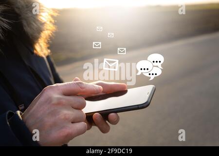 Unrecognizable man holding a smartphone and getting notifications while standing outdoors Stock Photo