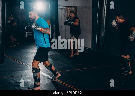 Boxer man during boxing hitting heavy bag at training fitness gym Stock Photo