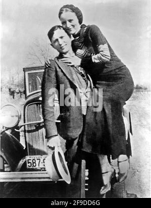 1934 , Arkansas , USA : The famous gangsterns  BONNIE PARKER  ( 1910 - 1934 ) and CLYDE BARROW ( 1909 - 1934 ). Contrary to popular belief the two never married. They were in a long standing relationship. Posing in front of a 1932 Ford V8 automobile where Bonnie and Clyde dead on May 23, 1934 . Unknown photographer . - OUTLAWS - KILLER - ASSASSINO - delinquente - criminalità organizzata  - GANGSTERN - Bos - CRONACA NERA - CRIMINALE - car - automobile - hat - cappello - embrace - abbraccio ---  Archivio GBB Stock Photo