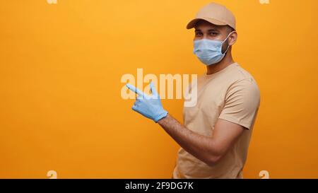 Young man with medical mask and gloves pointing finger on empty space. High quality photo Stock Photo