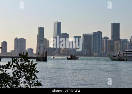 Tug boat going to save a yacht from the ocean in the Biscayne bay harbor inlet during sunset. Downtown Miami cityscape in the background. Stock Photo