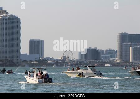 Boats traveling along Biscayne bay Brickell and Downtown Miami cityscape in the background. Boats are parking in the bay inlet to watch the sunset Stock Photo