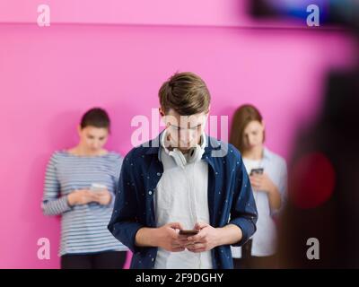 group of diverse teenagers use mobile devices while posing for studio photo Stock Photo