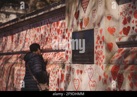 Westminster, London | UK - 2021.04.17: Lady writing names on The National COVID Memorial Wall painted with red hearts on beautiful sunny day Westminster, London | UK - 2021.04.17: Lady writing names on The National COVID Memorial Wall painted with red hearts on beautiful sunny day