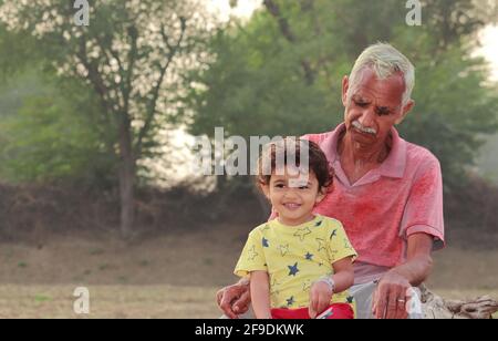 Close-up of Senior Grandpa and little grandson sitting together in the field Stock Photo