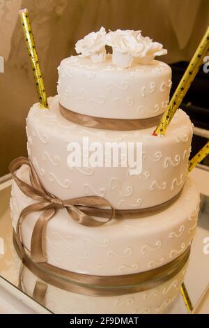 A closeup shot of a four-tier white wedding cake beautifully designed with a ribbon Stock Photo