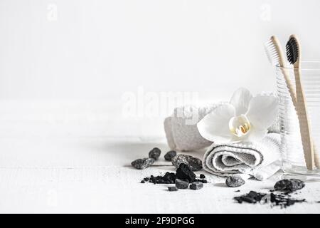 Still life with organic bamboo brushes and activated carbon powder and an orchid flower as a decorative element. Oral hygiene and dental care. Stock Photo