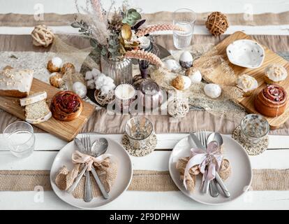 A festive table with beautiful dishes, decorative items and pastries. Easter table setting design idea. Stock Photo