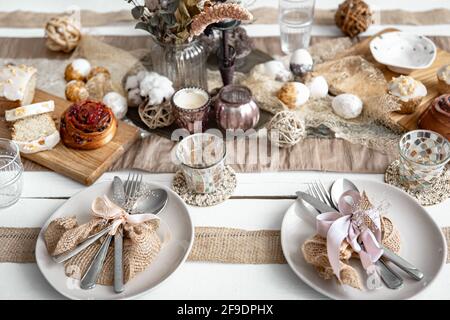 A festive table with beautiful dishes, decorative items and pastries. Easter table setting design idea. Stock Photo
