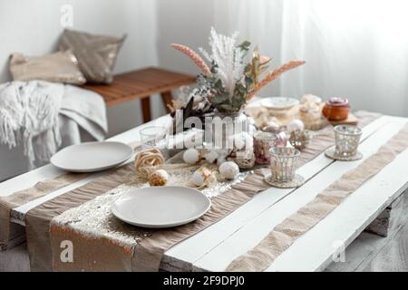 Empty plates and glasses on a decorated dining table for the Easter holiday. Beautiful hygge-style table setting. Stock Photo
