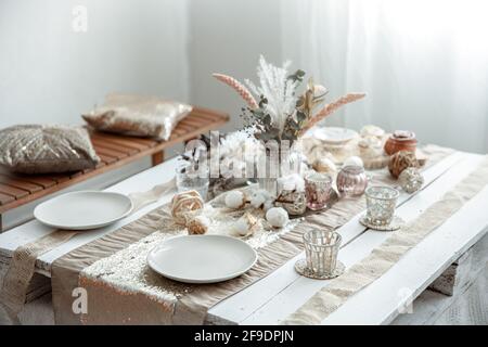 Empty plates and glasses on a decorated dining table for the Easter holiday. Beautiful hygge-style table setting. Stock Photo