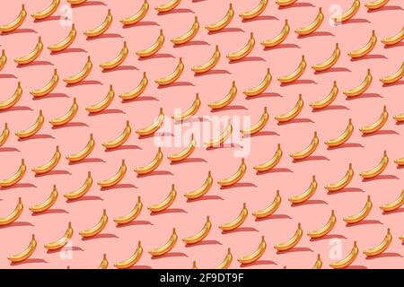 Trendy sunlight Summer pattern  yellow banana slice on bright light pink background. Minimal summer concept. Stock Photo